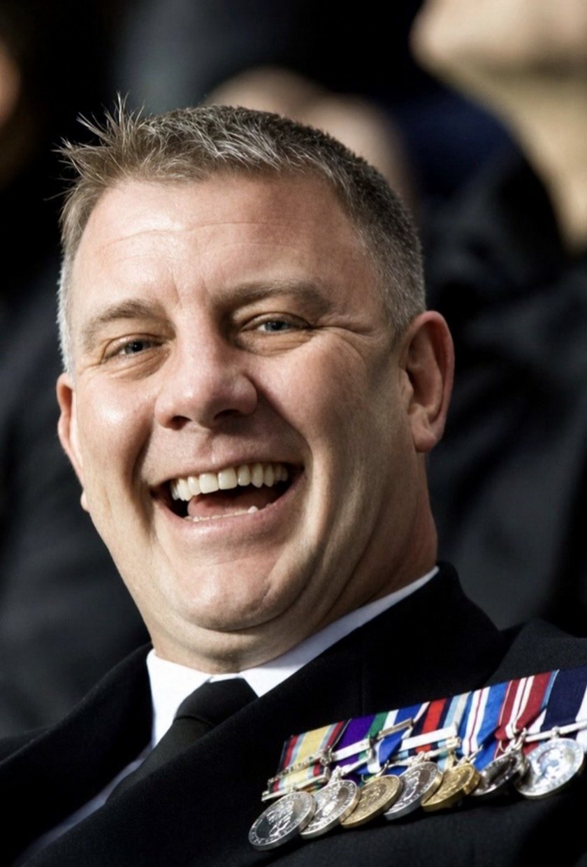 Paul Newman in Royal Navy uniform, wearing his service medals, laughing.